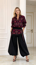 Front full view of woman wearing burgundy geometric print blouse and black balloon pants set